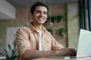 smiling-freelancer-copywriter-using-laptop-working-from-home-min